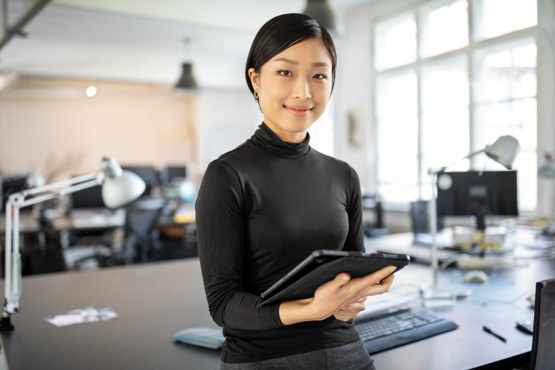 Portrait of young businesswoman standing in office with a digital tablet. Confident asian businesswoman in office.