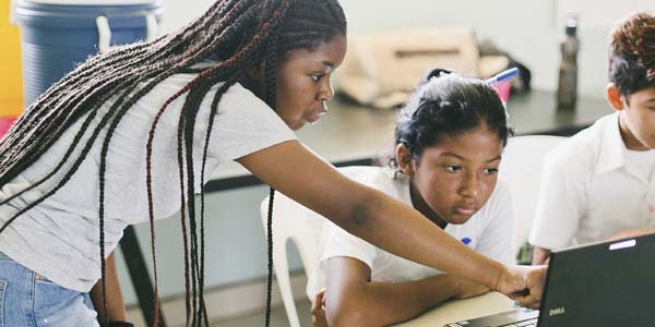 Two african american girls working at a computer.